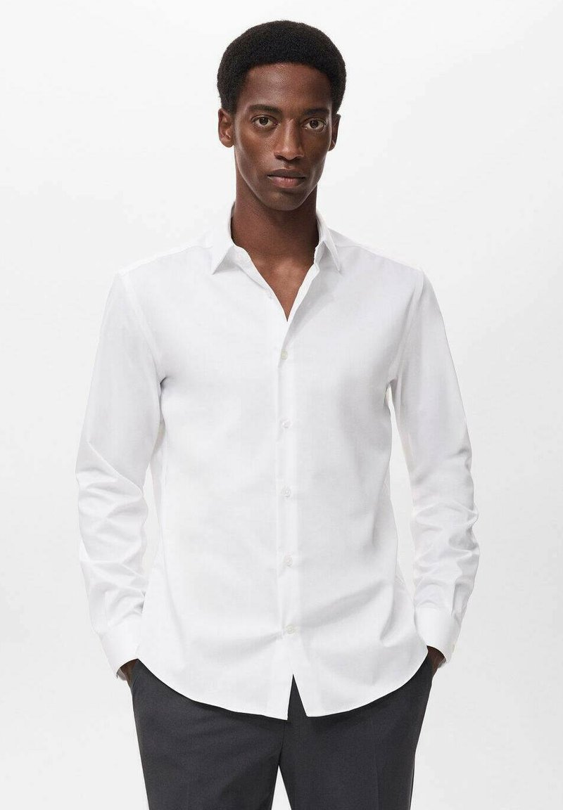 Camicia bianca a maniche lunghe con colletto classico, apertura con bottoni e orlo dritto. Realizzata in tessuto morbido, presenta una vestibilità su misura.