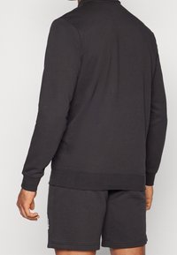 Sudadera gris oscuro con mangas largas, puños acanalados y un cuello redondo, combinada con pantalones cortos a juego, fabricados en suave tela de algodón.