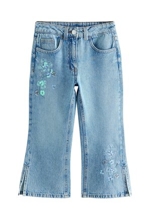 Jeans de mezclilla de color azul claro con un corte acampanado, que presentan adornos de lentejuelas florales en el frente y aberturas en el dobladillo.