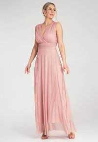 Długa, zwiewna różowa sukienka z plisowanym gorsetem i dekoltem w kształcie litery V. Gładki materiał z dopasowanym stanikiem, charakteryzująca się łagodnym opadaniem i warstwową spódnicą.