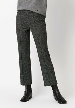 Dopasowane spodnie z czarno-szarego tweedu o prostym kroju nogawki, z subtelnymi teksturami i pionowymi szwami, zestawione z czarnymi botkami za kostkę.