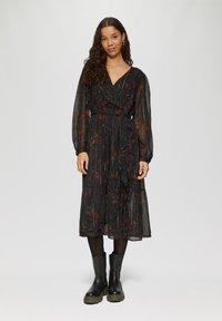 Schwarzes Blumen-Wickelkleid mit langen Ärmeln, das einen gestuften Rock, einen gerafften Saum und einen Stoffgürtel aufweist. Strukturiertes, durchsichtiges Material mit roten Akzenten.