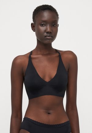 Black seamless bralette with a deep V-neck, scalloped edges, and adjustable straps. Smooth texture and lightweight design.