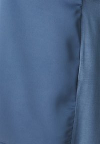 Blått stoff med en jevn, matt tekstur og en svak glans. Har rene kanter og minimal søm, noe som indikerer et enkelt, moderne design.