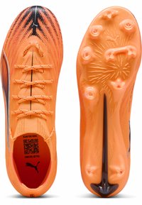 Scarpe da calcio Puma di un brillante arancione mostrate da sopra e dal suola, con accenti neri, lacci e tacchetti sagomati per una migliore trazione.