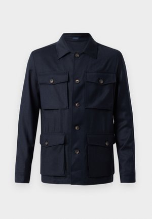 Chaqueta navy con un cierre de botones en la parte delantera, cuatro bolsillos frontales, un cuello clásico y una textura de tela suave. Presenta botones marrones y una forma entallada.