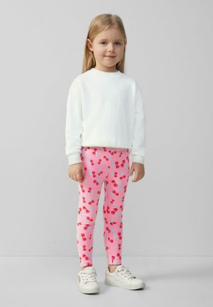 Witte sweatshirt en roze leggings met rode kersen en blauwe accenten. Glad stofoppervlak, aansluitend ontwerp en witte schoenen.
