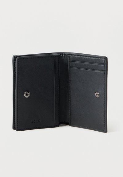 Portefeuille bifold en cuir noir ouvert montrant une pochette à monnaie boutonnée et trois emplacements pour cartes sur un fond clair uni.