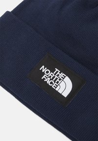 Berretto a maglia blu navy con una toppa in tessuto nera che presenta il logo "THE NORTH FACE" in bianco e l'iconica grafica della mezza cupola.