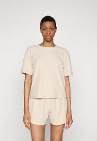 Beige ribbet bomulds top med korte ærmer og rund halsudskæring, parret med matchende shorts med elastisk talje.