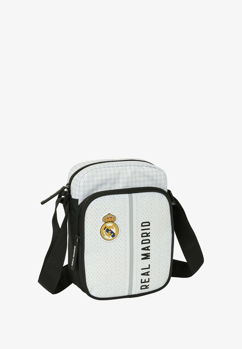 Biały prostokątny torebka crossbody z czarnymi akcentami, z logo Real Madrytu, pionową paskiem i perforowaną teksturą. Zamek błyskawiczny, regulowany pasek.