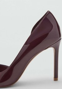 Bordowy lakierowany szpilka z zamszowym wykończeniem i migdałowym noskiem. Obcas ma około 10 cm wysokości i jest ozdobiony delikatnym złotym akcentem.