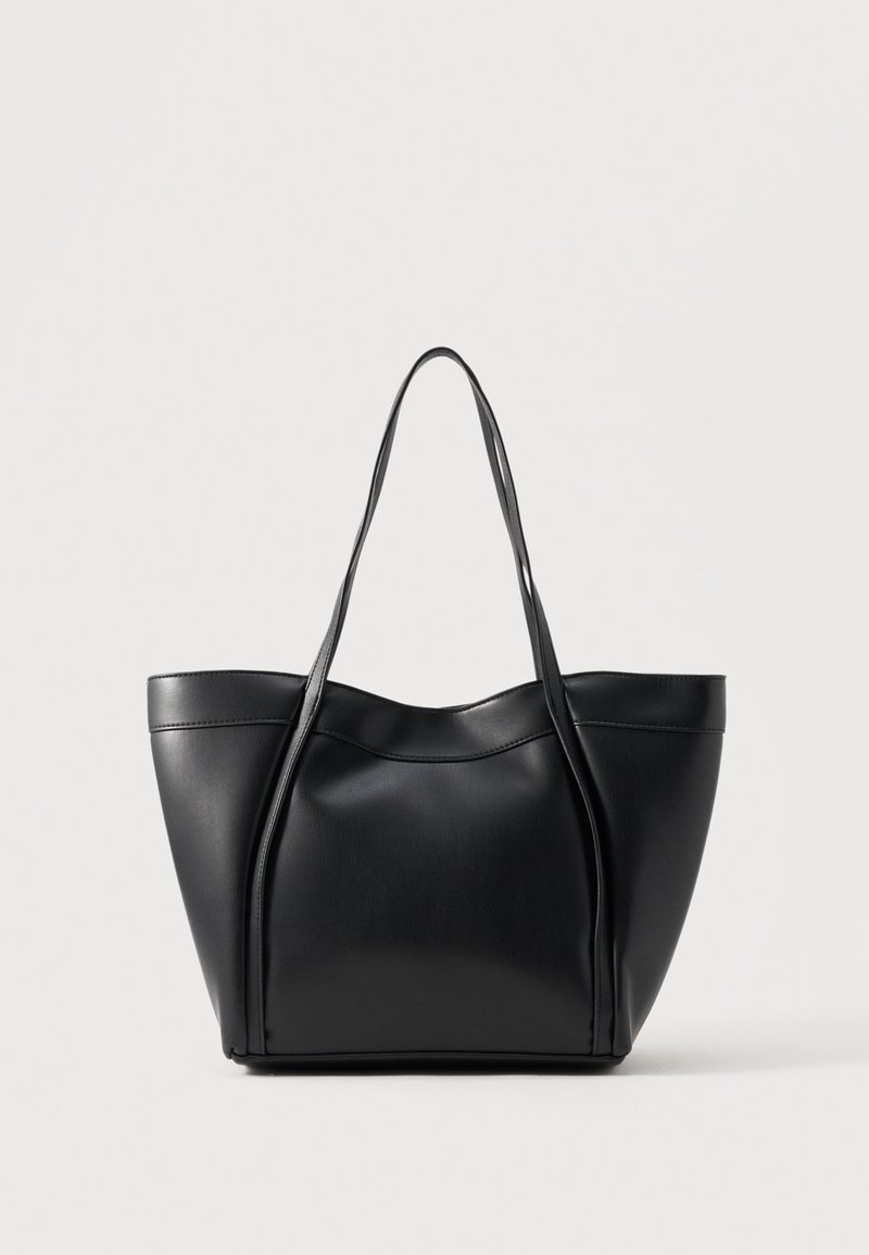 Sac cabas en cuir noir avec deux longues anses et un bord supérieur légèrement incurvé, présenté sur un fond clair uni.