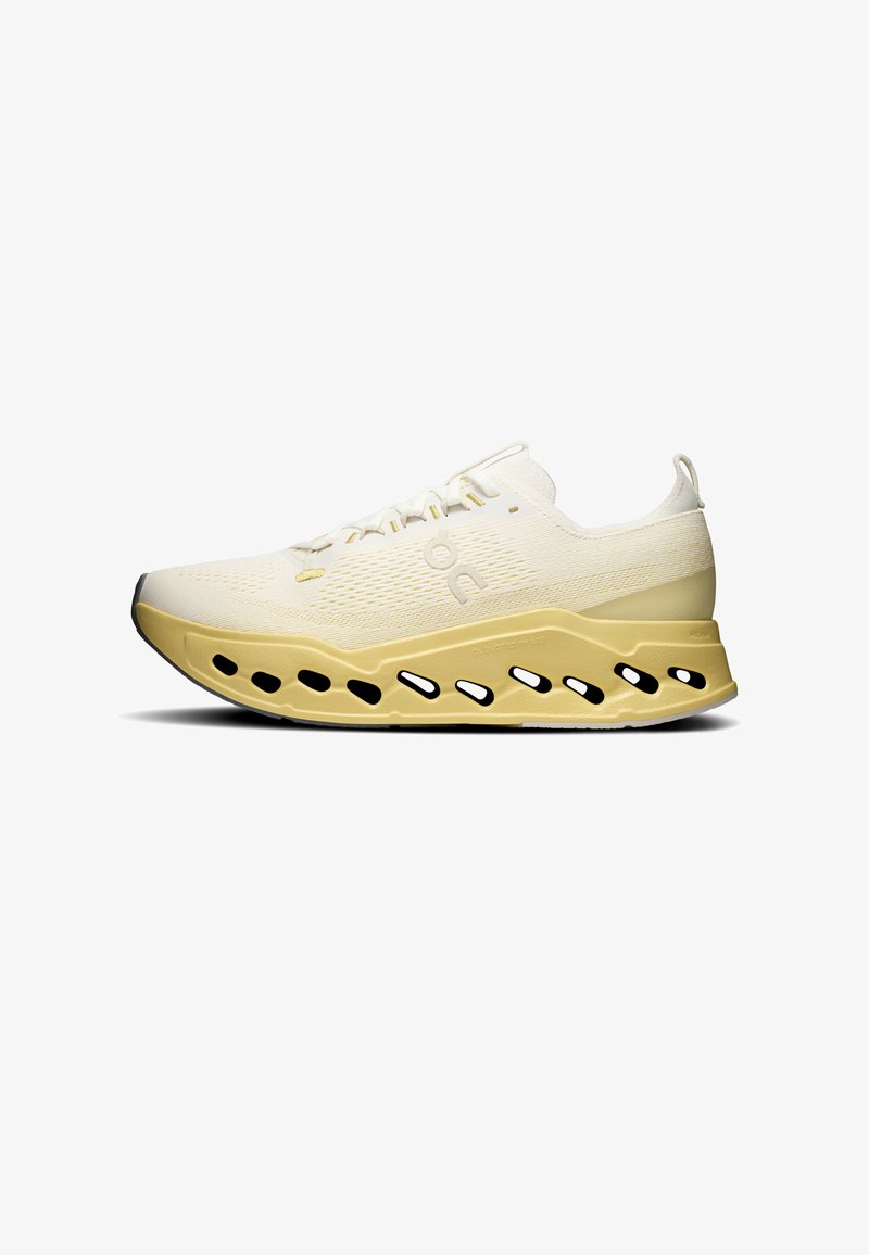 Chaussure de sport jaune et blanche avec une semelle épaisse et ventilée comportant des découpes ovales et une tige en mesh texturé, vue de côté.