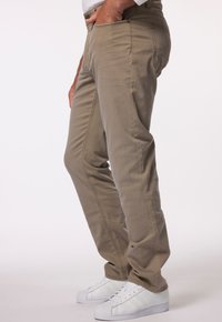 Pantaloni khaki con una superficie liscia, design a gamba dritta, tasche laterali e chiusura con bottone, abbinati a sneaker bianche.