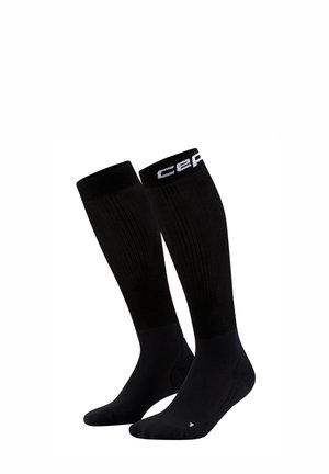 Een paar zwarte kniehoge compressiekousen met geribbelde structuur en witte logotekst aan de bovenrand.