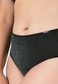 Zwarte hooggesneden broek met een glinsterende textuur, elastische tailleband en een klein metalen merklabel aan de voorkant.