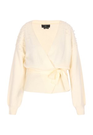 Kreminė megztinė su ilgomis rankovėmis, su iškiliais juostiniais apatinias ir puošniomis perlų formos detalėmis ant pečių. Minkšta tekstūra ir užrišimo uždarymas.