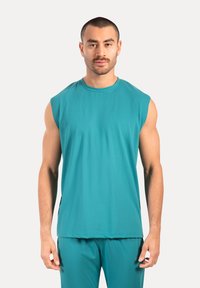 Vielseitiges ärmelloses sportliches Oberteil in Teal mit Rundhalsausschnitt, aus einem glatten, dehnbaren Stoff gefertigt. Es hat eine lockere Passform und minimale Nähte für optimalen Komfort.