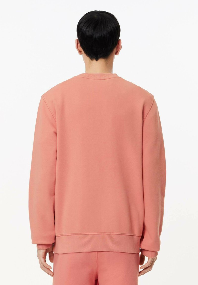 Felpa rosa con orlo e polsini a coste, realizzata in tessuto morbido. Presenta un classico colletto a girocollo e una vestibilità rilassata.