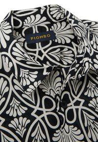 Overhemd met kraag, voorzien van een zwart-wit bloemenpatroon, gemaakt van stof met een gladde textuur. Label leest "PIOMBO," met een donkerblauwe achtergrond.
