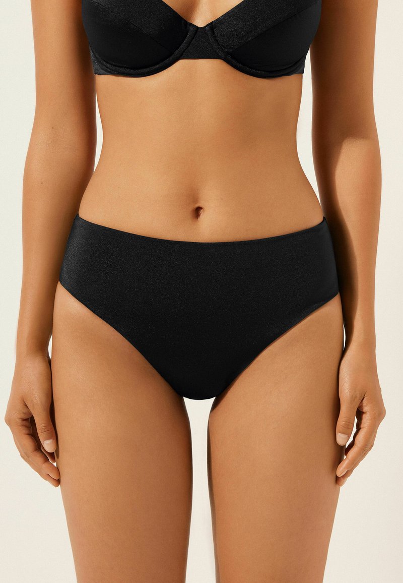 Czarny bikini o wysokim stanie, wykonany z gładkiego materiału, z prostym wzornictwem. Brak widocznych wzorów lub detali z hardware.