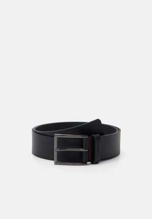 Ceinture en cuir noir au toucher lisse avec une boucle en métal argenté. Présente des surpiqûres rouges sur la boucle en cuir pour un détail supplémentaire.