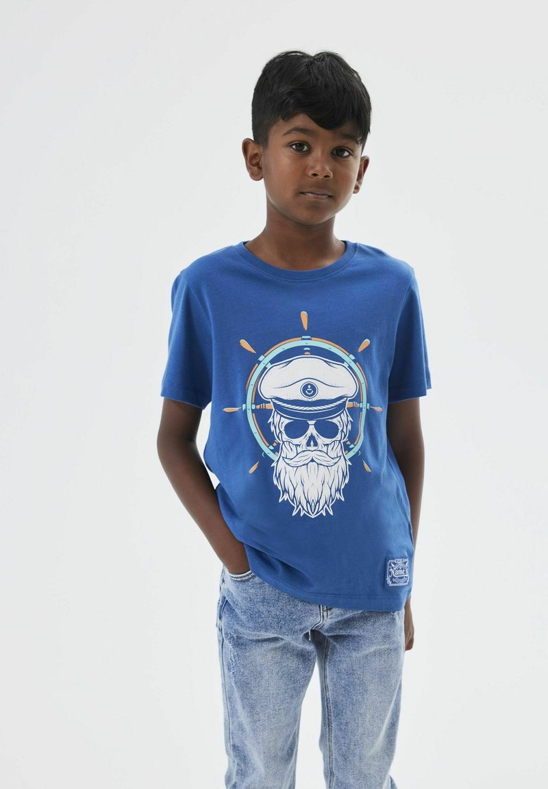 Camiseta de algodón azul con un gráfico de una calavera con un sombrero de capitán y barba, rodeada por un círculo con acentos naranjas y azules.