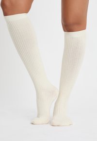 Knielange cremefarbene Socken mit gerippter Struktur, aus weichem Material, in einfarbiger Ausführung und mit elastischem oberen Rand für einen sicheren Sitz.