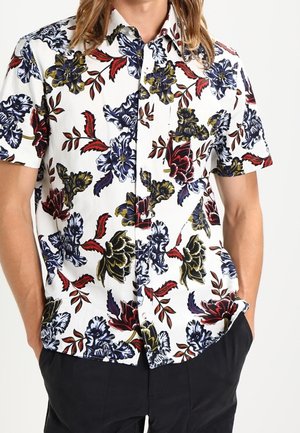 Korte mouwen shirt met een witte achtergrond en kleurrijke bloempatronen in blauw, rood en geel. Met knoopsluiting en een relaxte pasvorm.