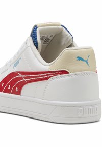 Baskets en cuir blanc avec des accents rouges et bleus. Présentent un talon texturé, une semelle en caoutchouc et un logo PUMA. Chiffres "1, 2, 3" sur le côté.