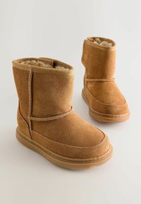 Brūnas zamšādas potītes zābaki ar mīkstu, plush iekštelpu, ar šuvju detaļām un gumijas zoli, kas nodrošina ilgnoturību un komfortu.