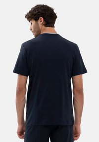 Herrtröja i marinblå bomull med rund halsringning och korta ärmar. Slät textur, avslappnad passform, infälld fåll och minimalistisk design.