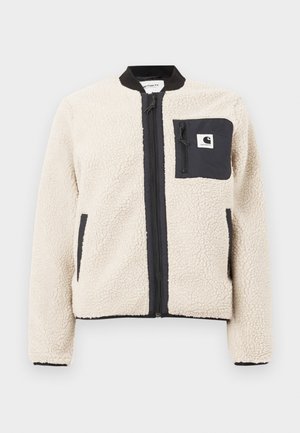 Beige fleece-takki mustalla vetoketjulla ja taskuilla. Ominaisuuksia ovat pehmeä rakenne, ribbineule kaulus ja joustavat hihansuut. Sisältää logopatchin rinnassa.