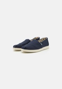 Mørkeblå canvas slip-on sko med rund tå, elastiske detaljer og en kremfarget gummisåle. Innvendig har de et sikksakkmønster.