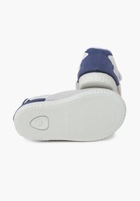 Sneaker con una parte superiore grigia morbida, accenti blu scuro, suola in gomma texturizzata e una distintiva intersuola bianca. Caratterizzate da un branding minimal e dettagli a contrasto.