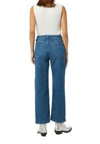 Jeans w wysokim stanie, szerokie nogawki, w kolorze niebieskim, o luźnym kroju, z kieszeniami z przodu i naszywanymi kieszeniami z tyłu. Wykonane z denimu o gładkiej strukturze.