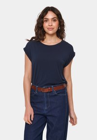 Jūras zilas krāsas īsām piedurknēm T-krekls ar apaļu izgriezumu, saskaņots ar tumšiem džinsiem un brūnu teksturētu jostu. Gluda auduma un brīvs griezums.