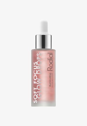Transparent glass bottle with a gradient pink hue, featuring a white dropper and silver accents. Label text includes "Soft Focus Glow Drops" and "Rodial."