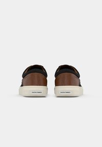 Brune lædersneakers med sorte accenter, hvide gummisåler og lav profil. Har et quiltet design og logo på hælen.