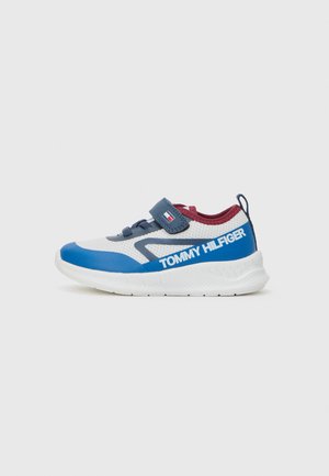 Sapatilha azul e branca com parte superior em malha texturizada, faixa de velcro e sola de borracha. Apresenta o logótipo "TOMMY HILFIGER" na lateral.