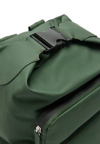 Zielony wodoodporny plecak wykonany z teksturowanego materiału. Posiada dużą klapkę zamykającą oraz boczną kieszeń zapinaną na zamek z srebrnymi akcentami.