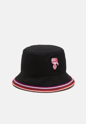 Czarna kapelusz typu bucket hat z wielokolorowym paskowanym rondem i małą różową naszywką z postacią z kreskówki z przodu.
