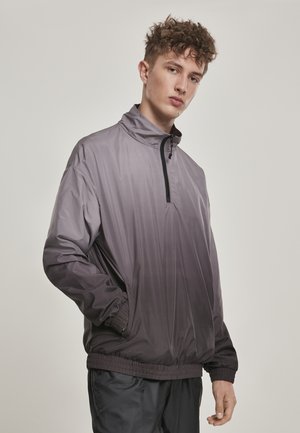 Lett pullover-jakke i gradient grå, med høy krage, halv-zip front, og elastiske mansjetter og hem. Glatt, blankt materiale.