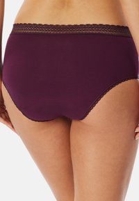 Lila bomullstrosa med spetskant midja, med en slät yta och ett design för full täckning. Inga ytterligare mönster eller detaljer synliga.