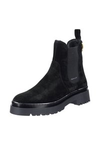 Czarne zamszowe botki za kostkę z elastycznymi panelami bocznymi, pętelką do zakładania oraz masywną czarną gumową podeszwą z bieżnikiem dla lepszej przyczepności.