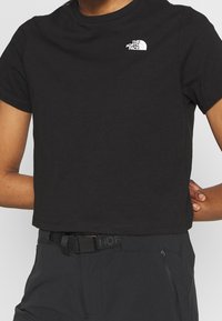 Svart kort t-shirt i bomull med korta ärmar och en vit logotyp av "The North Face" på vänster bröst.