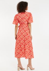Rot kariertes Midi-Kleid mit kurzen Puffärmeln, einer taillierten Taille und einem ausgestellten Rock. Verfügt über einen strukturierten Stoff und eine Bindeschließe im Rücken.