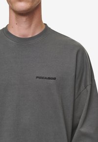 Gray cotton sweatshirt with a round neckline and dropped shoulders. Features an embossed logo on the chest in a darker shade.