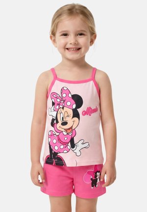 Jeune fille souriante portant un débardeur rose Minnie Mouse à pois et un short assorti avec un motif de chat de dessin animé.